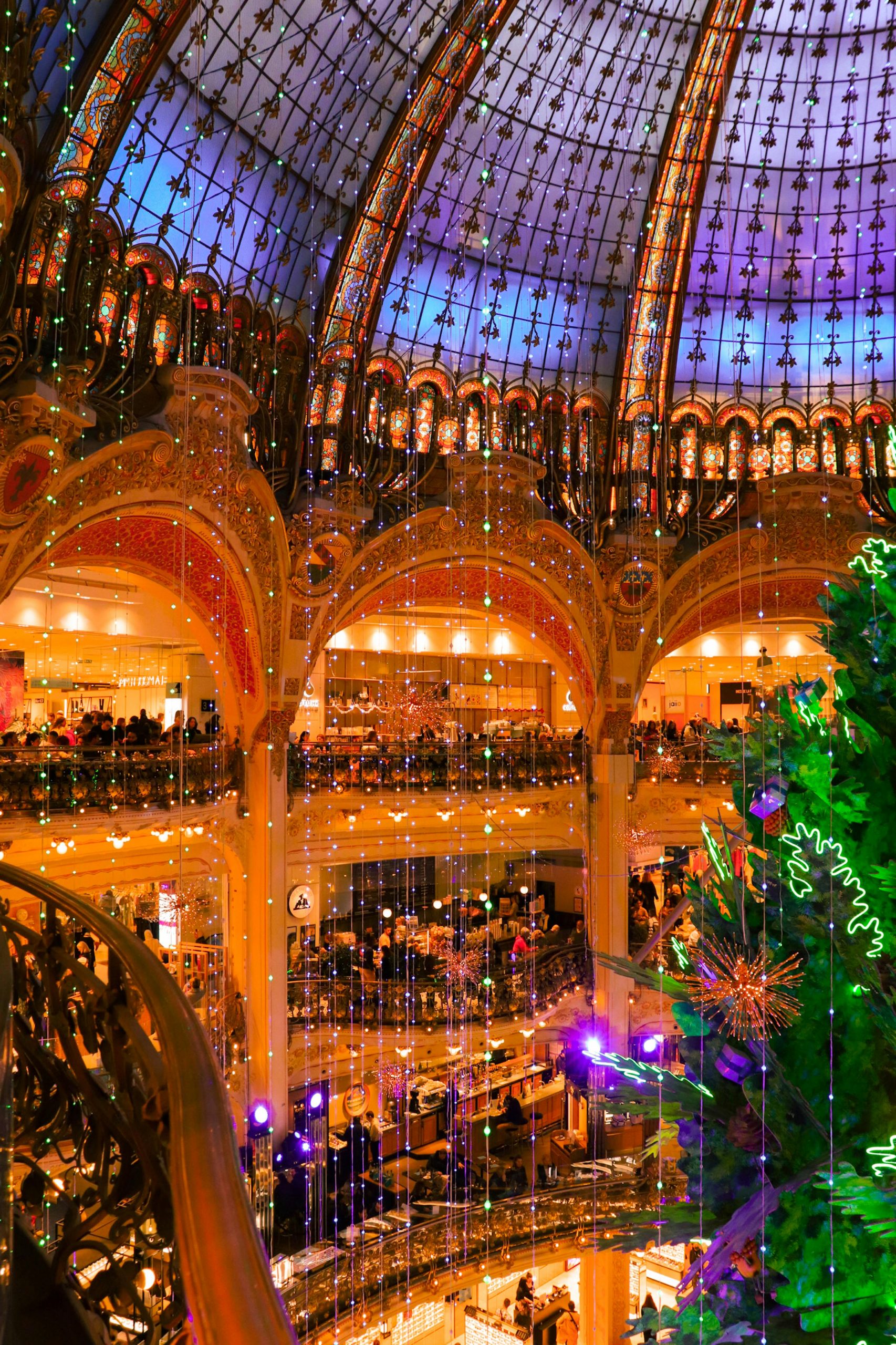 Illuminated view of a decorated Paris shopping mall interior during the holiday season.